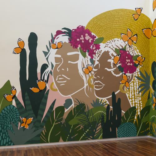 A mural depicting two women of color surrounded by cacti and butterflies.