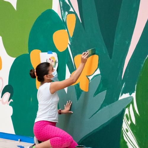 An artist paints a colorful mural.