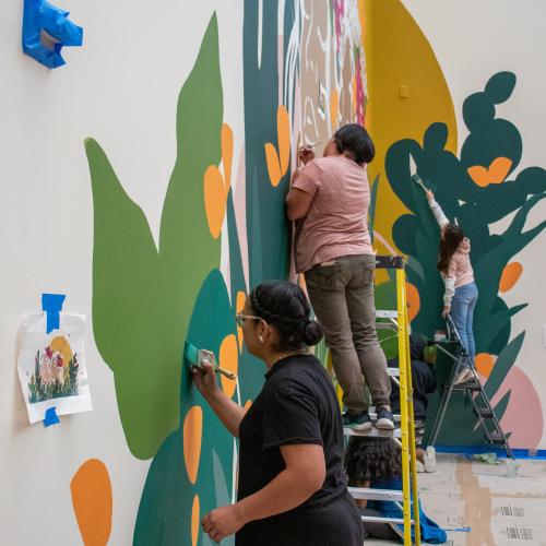 Artists work on a large mural.