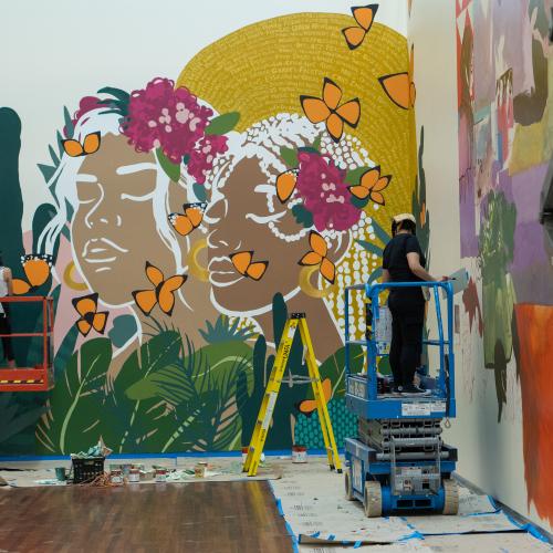 artists work on large colorful murals.