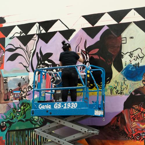 An artist paints a colorful mural.