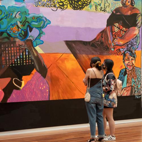 Two visitors stand in front of a colorful mural