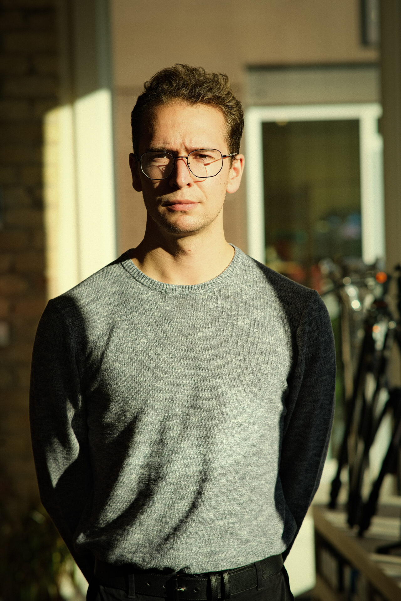 A photo of Christopher Woodward from the waist up. Dramatic lighting from a nearby window casts shadows on his face.