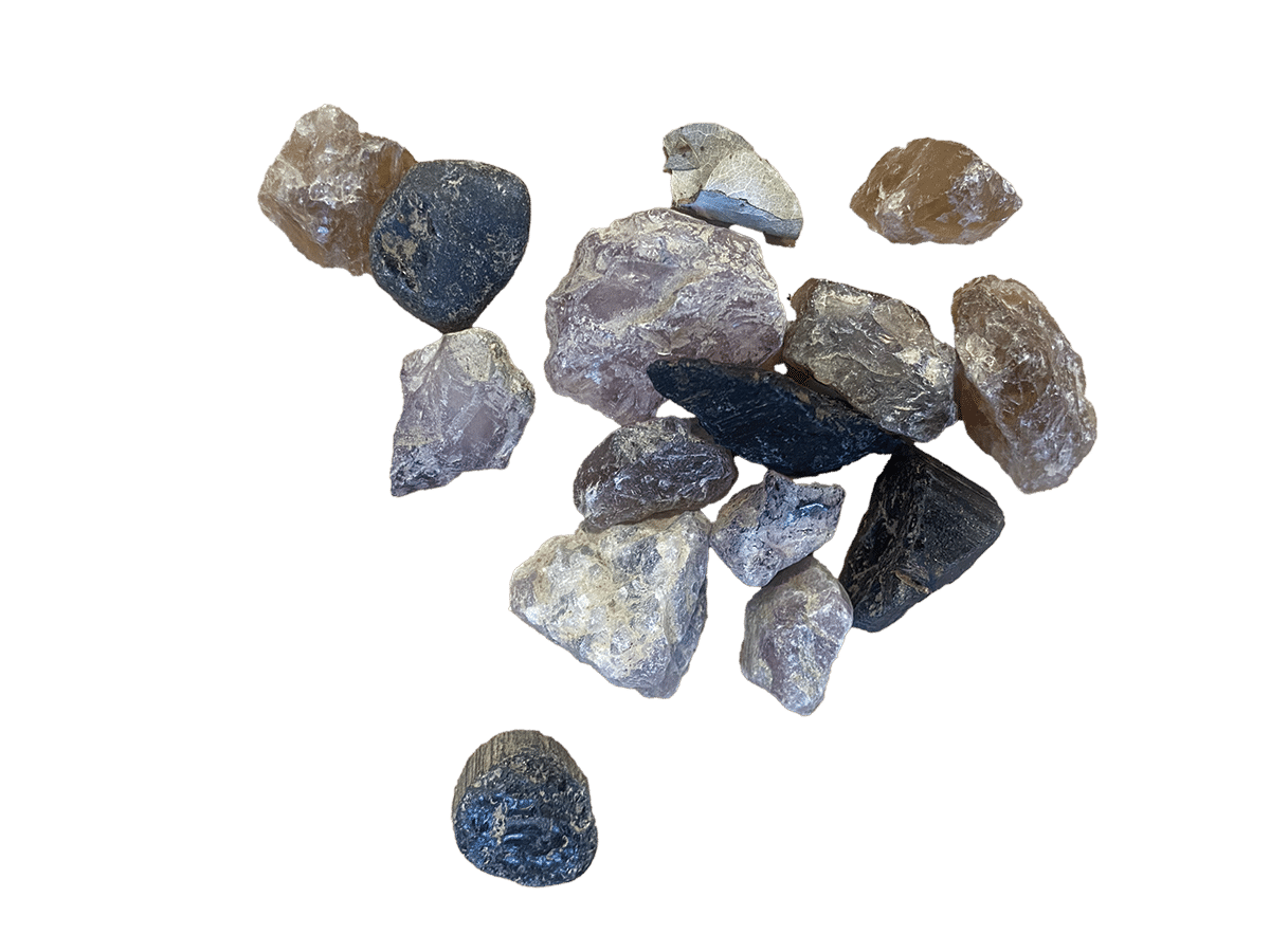 A group of unpolished, assorted minerals and rocks in various shapes and colors, including black, brown, gray, and lavender, displayed against a white background.