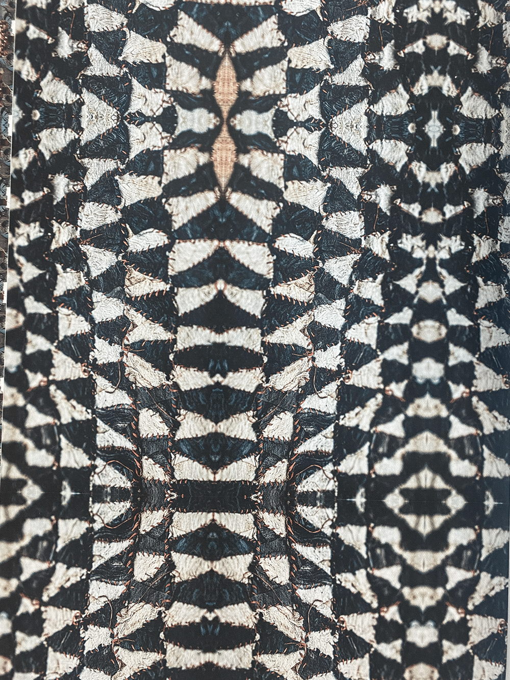 Close-up of a symmetrical, geometric pattern in black, white, and beige with a textured, woven appearance, resembling abstract shapes or scales arranged in mirrored rows and columns.
