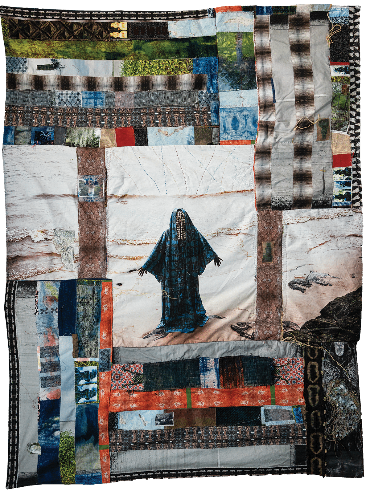 A textile artwork featuring a fabric collage border around a central image of a veiled figure in dark blue standing on a sandy landscape, with varied patterns and textures throughout.